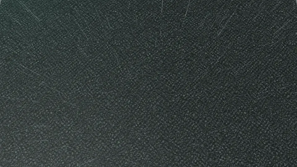 Rain streaks falling onto dark, rough asphalt